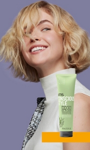 Smiling woman with a blonde bob next to a tube of KMS consciousstyle beach style creme